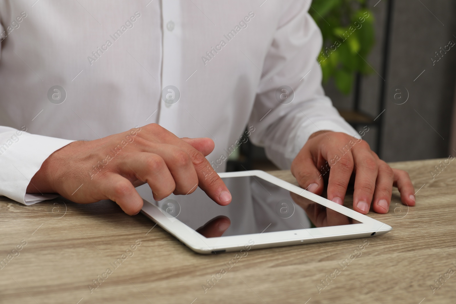 Photo of Businessman using tablet at wooden table, closeup. Modern technology