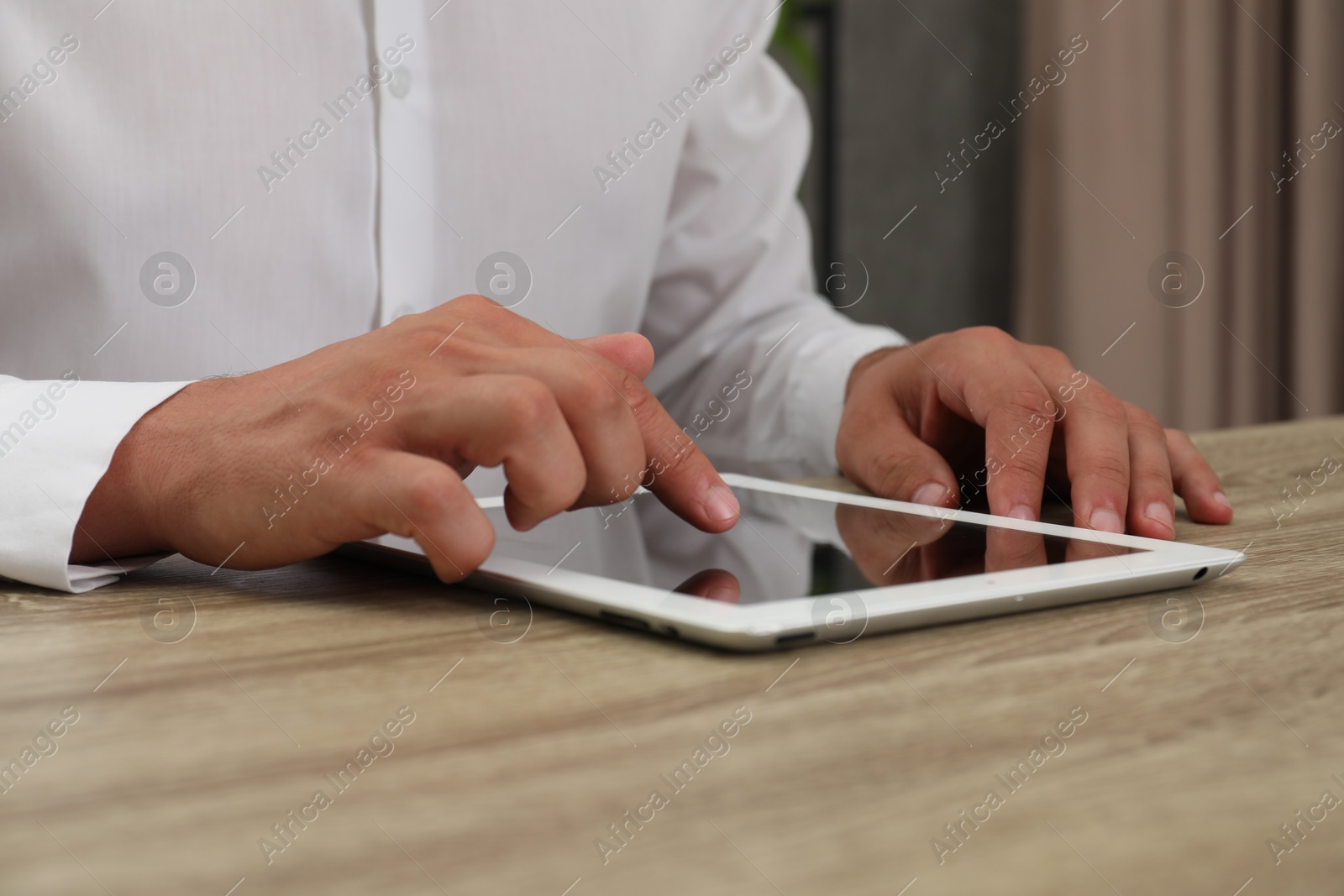 Photo of Businessman using tablet at wooden table, closeup. Modern technology