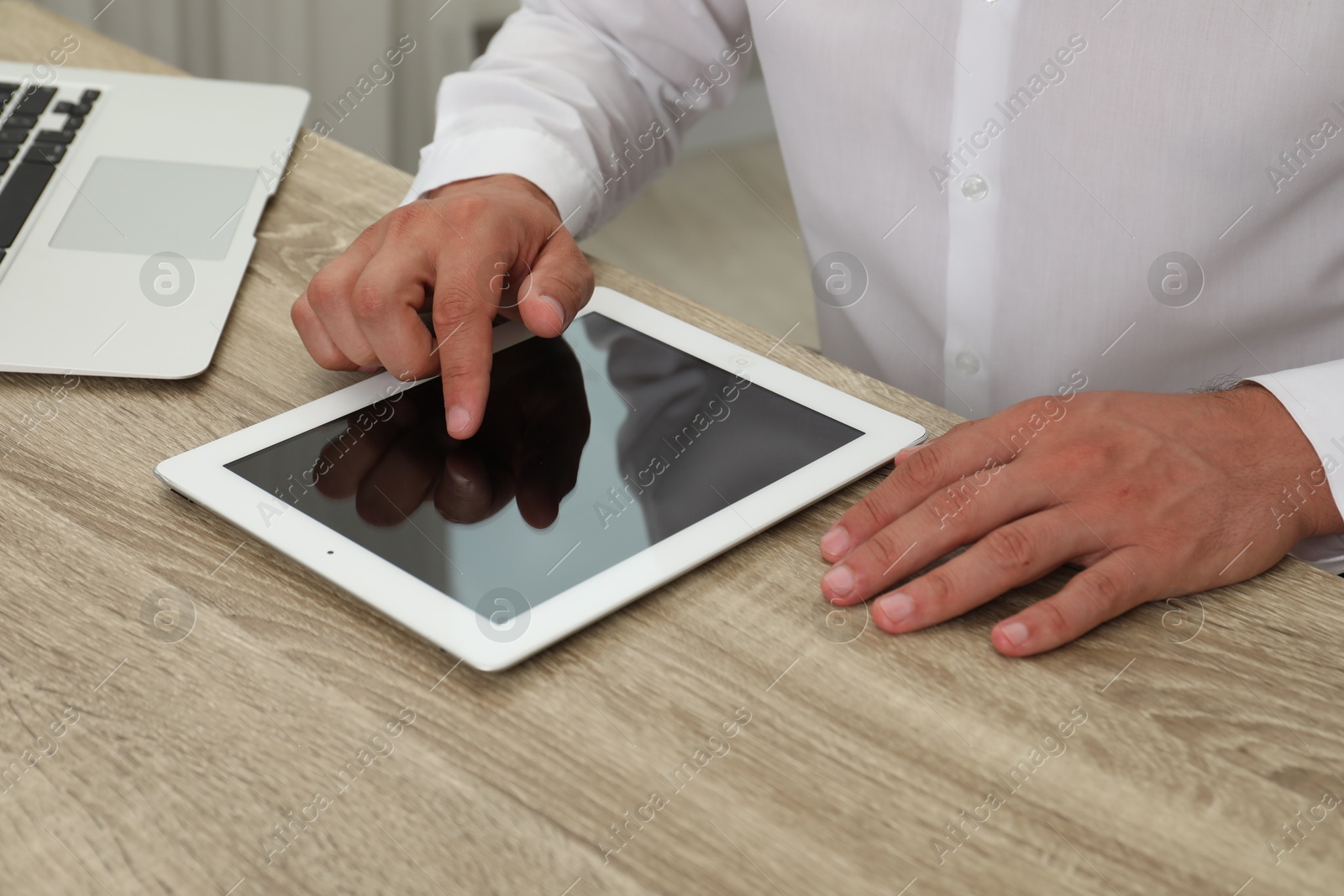 Photo of Businessman using tablet at wooden table, closeup. Modern technology