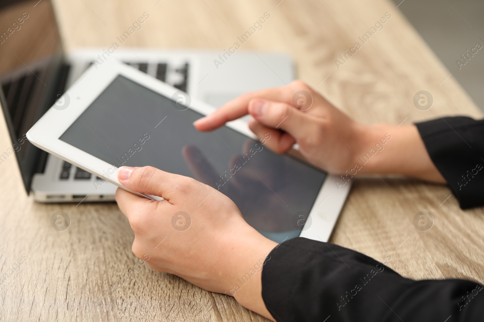 Photo of Businessman with tablet and laptop at wooden table, closeup. Modern technology