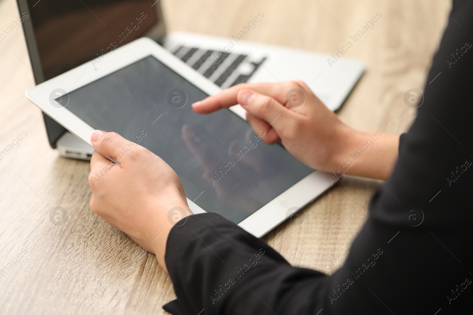 Photo of Businessman with tablet and laptop at wooden table, closeup. Modern technology