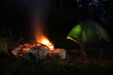 Photo of Bonfire and camping tent in forest at night