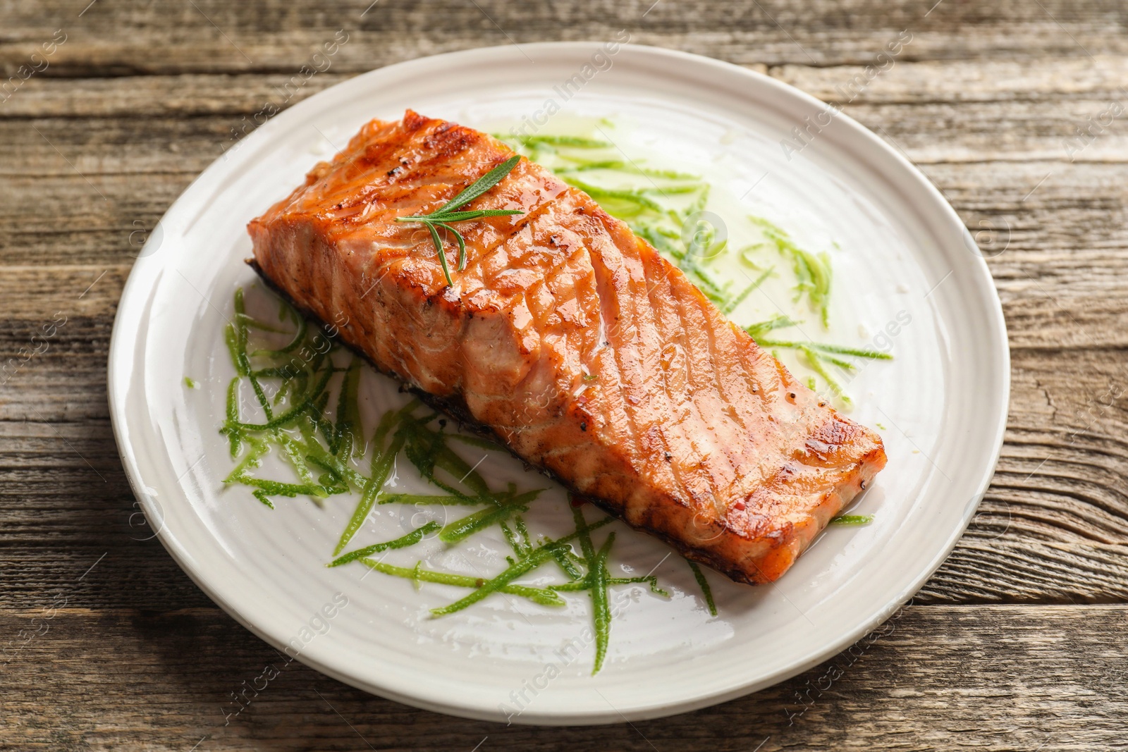 Photo of Delicious grilled salmon fillet served on wooden table, closeup