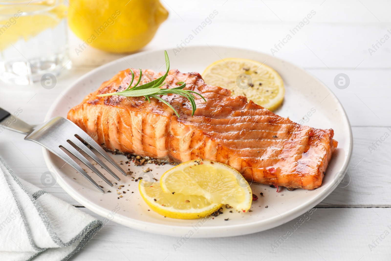 Photo of Delicious grilled salmon fillet served on white wooden table, closeup