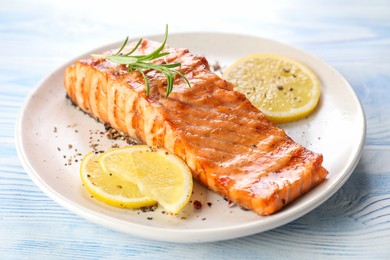 Photo of Delicious grilled salmon fillet served on light blue wooden table, closeup