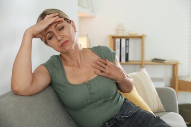 Menopause. Woman suffering from hot flash on sofa indoors