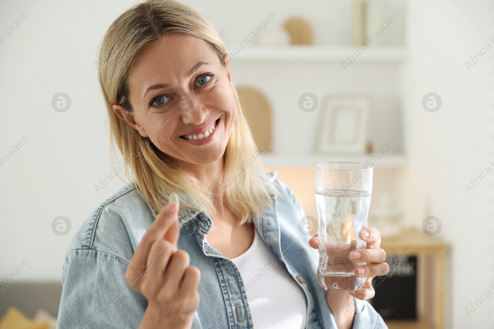 Photo of Menopause, hormone replacement therapy. Happy woman with pill and glass of water at home