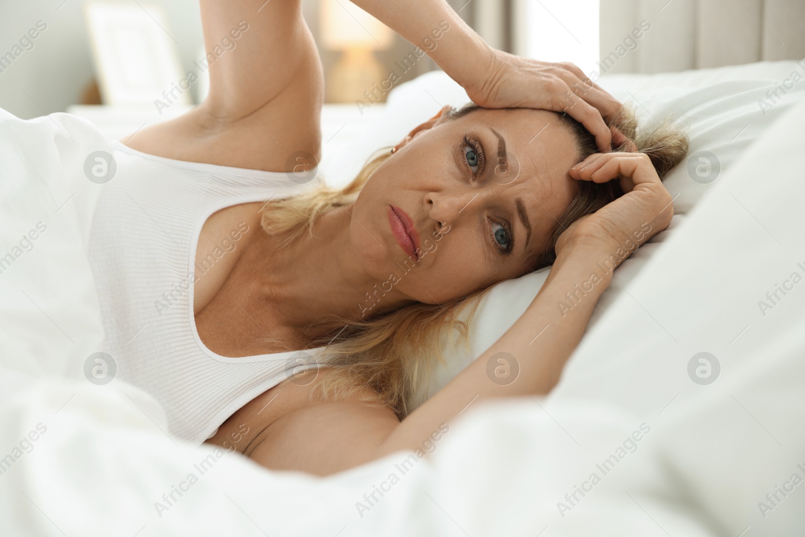 Photo of Menopause. Woman suffering from headache in bed at home