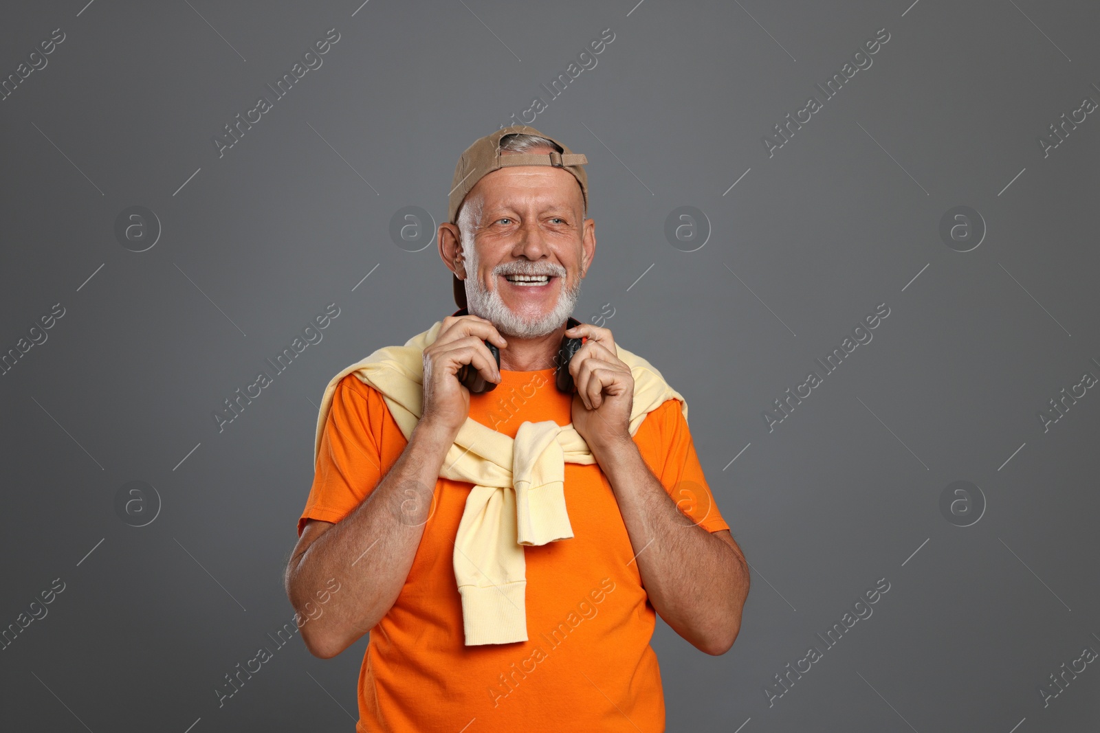 Photo of Portrait of happy senior man with headphones on grey background