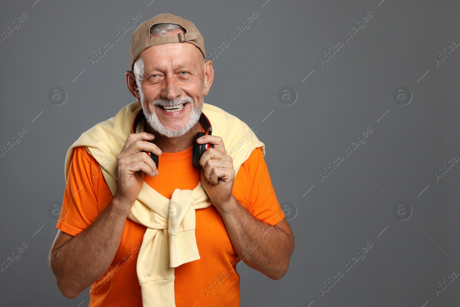 Photo of Portrait of happy senior man with headphones on grey background. Space for text