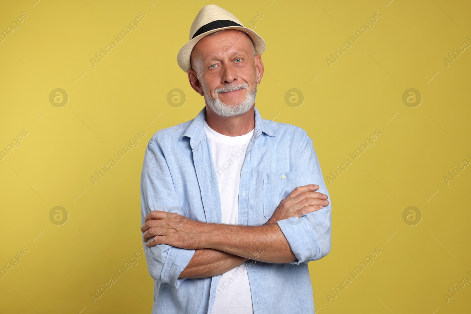 Photo of Portrait of handsome senior man with crossed arms on yellow background