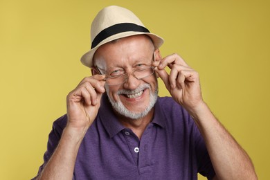 Portrait of happy senior man on yellow background