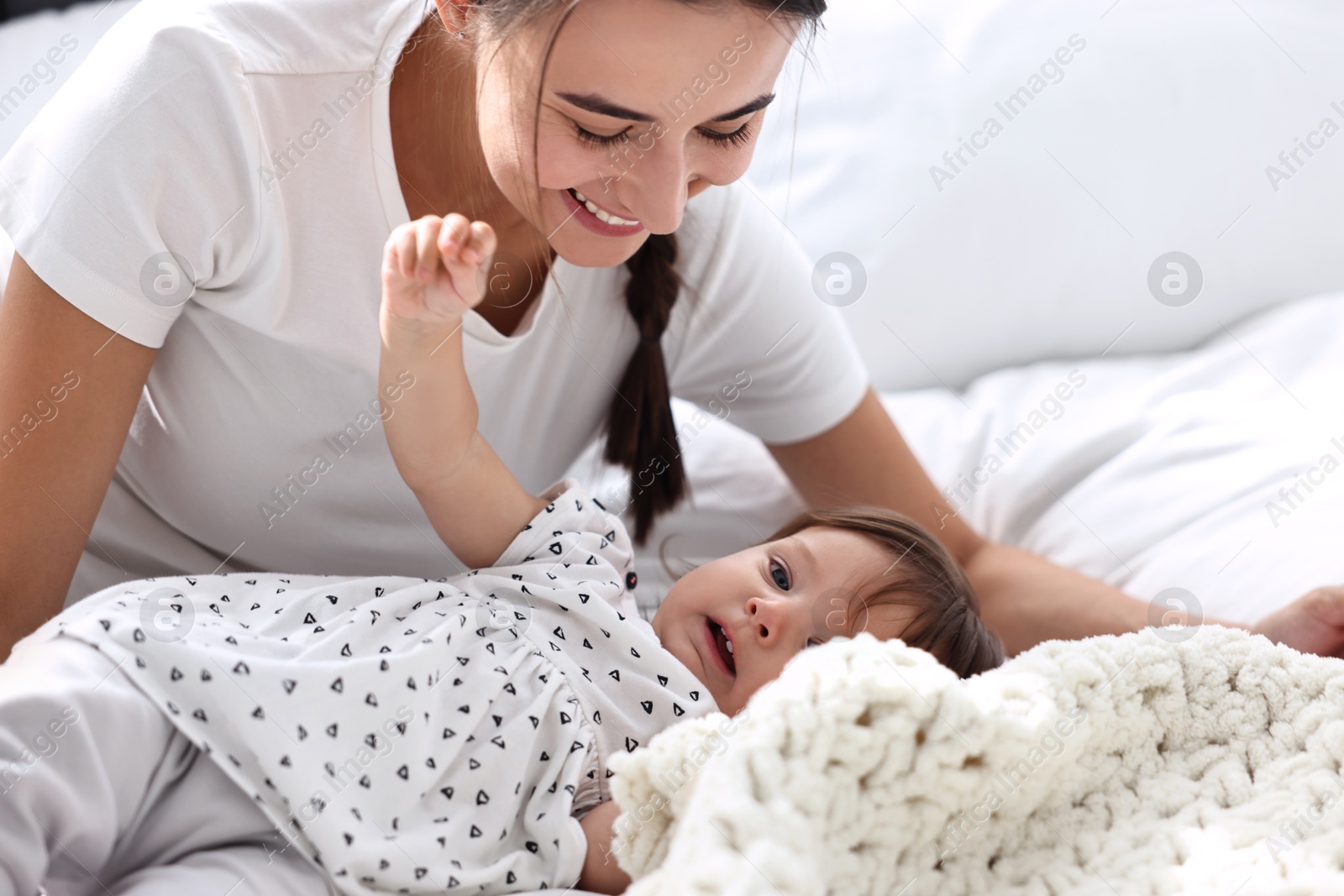 Photo of Beautiful young mother and her cute little baby on bed at home