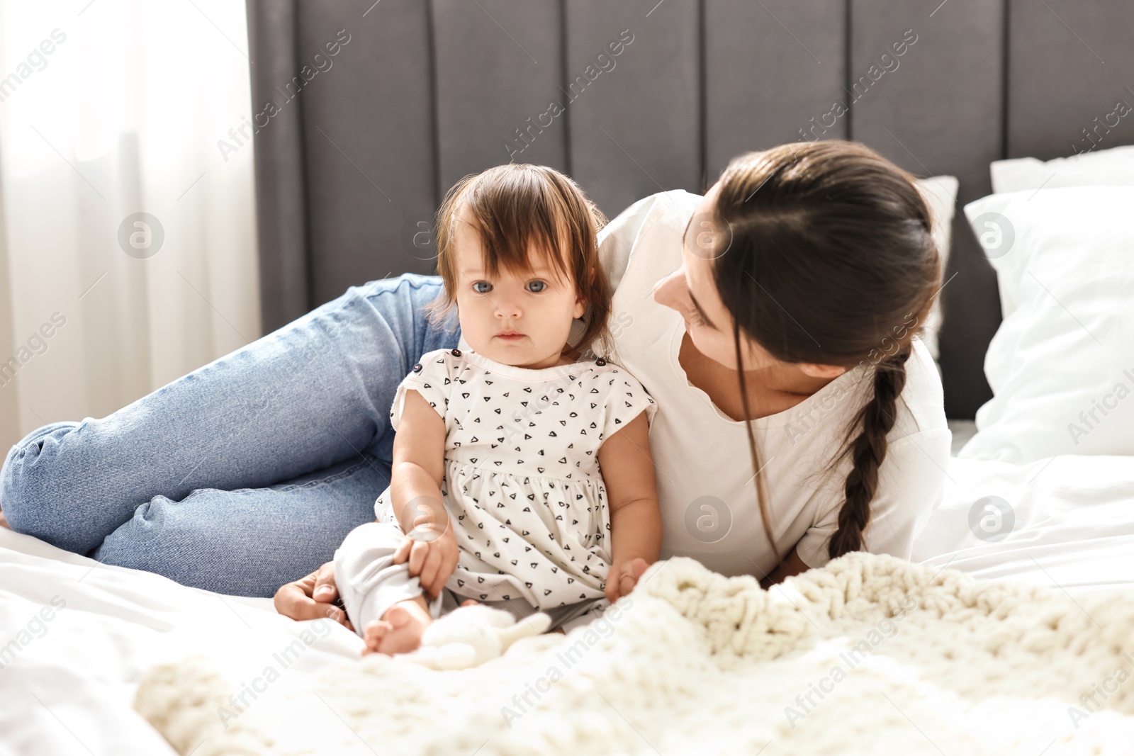 Photo of Beautiful young mother and her cute little baby on bed at home