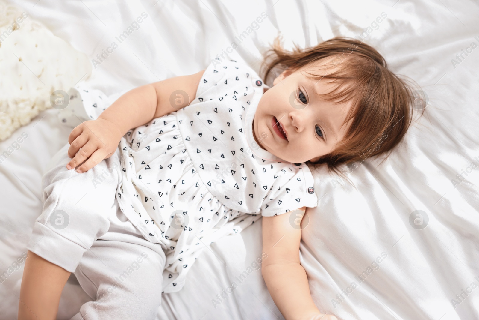 Photo of Cute little baby lying on soft bed, above view