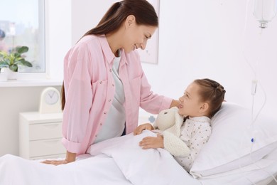 Photo of Mother and her little daughter on bed in hospital