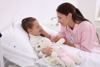 Mother and her little daughter on bed in hospital