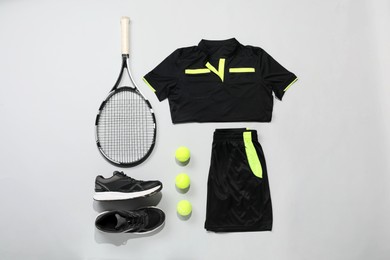 Photo of Tennis racket, balls and sportswear on light background, flat lay