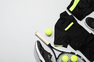 Photo of Tennis racket, balls and sportswear on light background, flat lay. Space for text