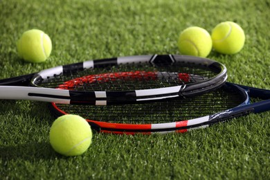 Photo of Tennis rackets and balls on green artificial grass, closeup