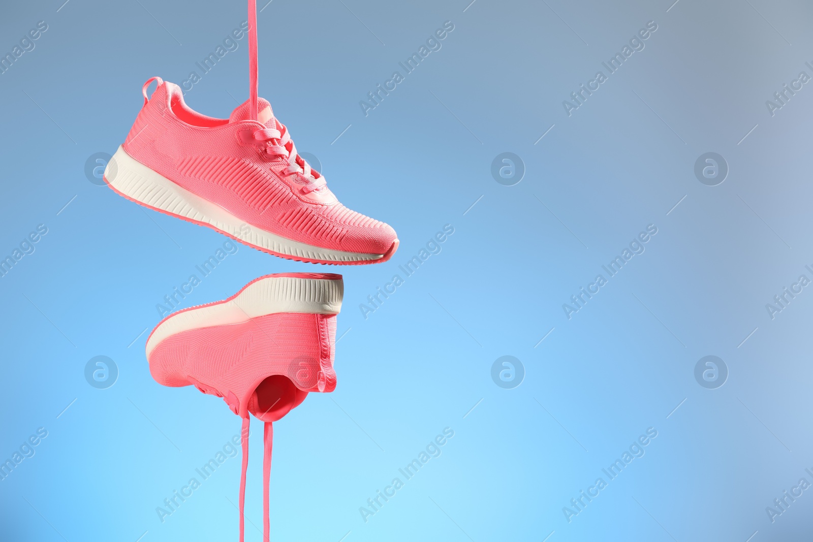 Photo of Pair of stylish sneakers in air against light blue background, space for text