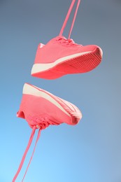 Photo of Pair of stylish sneakers in air against light blue background