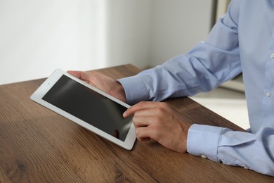 Photo of Businessman using tablet at wooden table, closeup. Modern technology