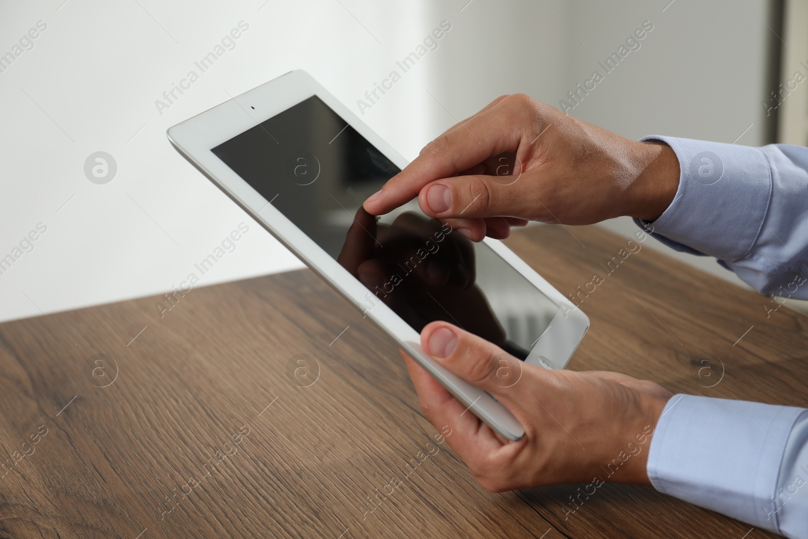 Photo of Businessman using tablet at wooden table, closeup. Modern technology