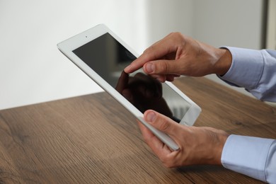 Photo of Businessman using tablet at wooden table, closeup. Modern technology