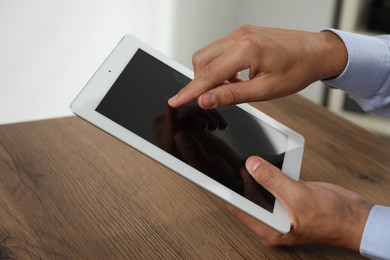 Photo of Businessman using tablet at wooden table, closeup. Modern technology