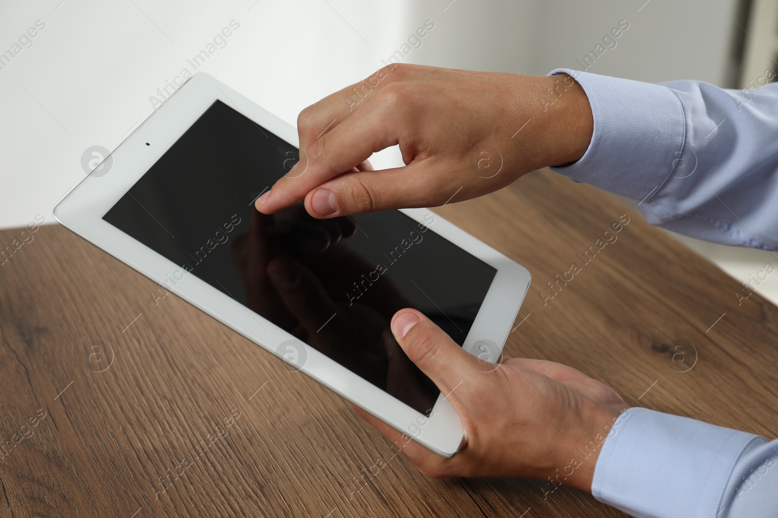 Photo of Businessman using tablet at wooden table, closeup. Modern technology