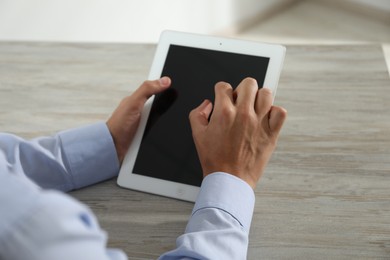 Photo of Businessman using tablet at wooden table, closeup. Modern technology