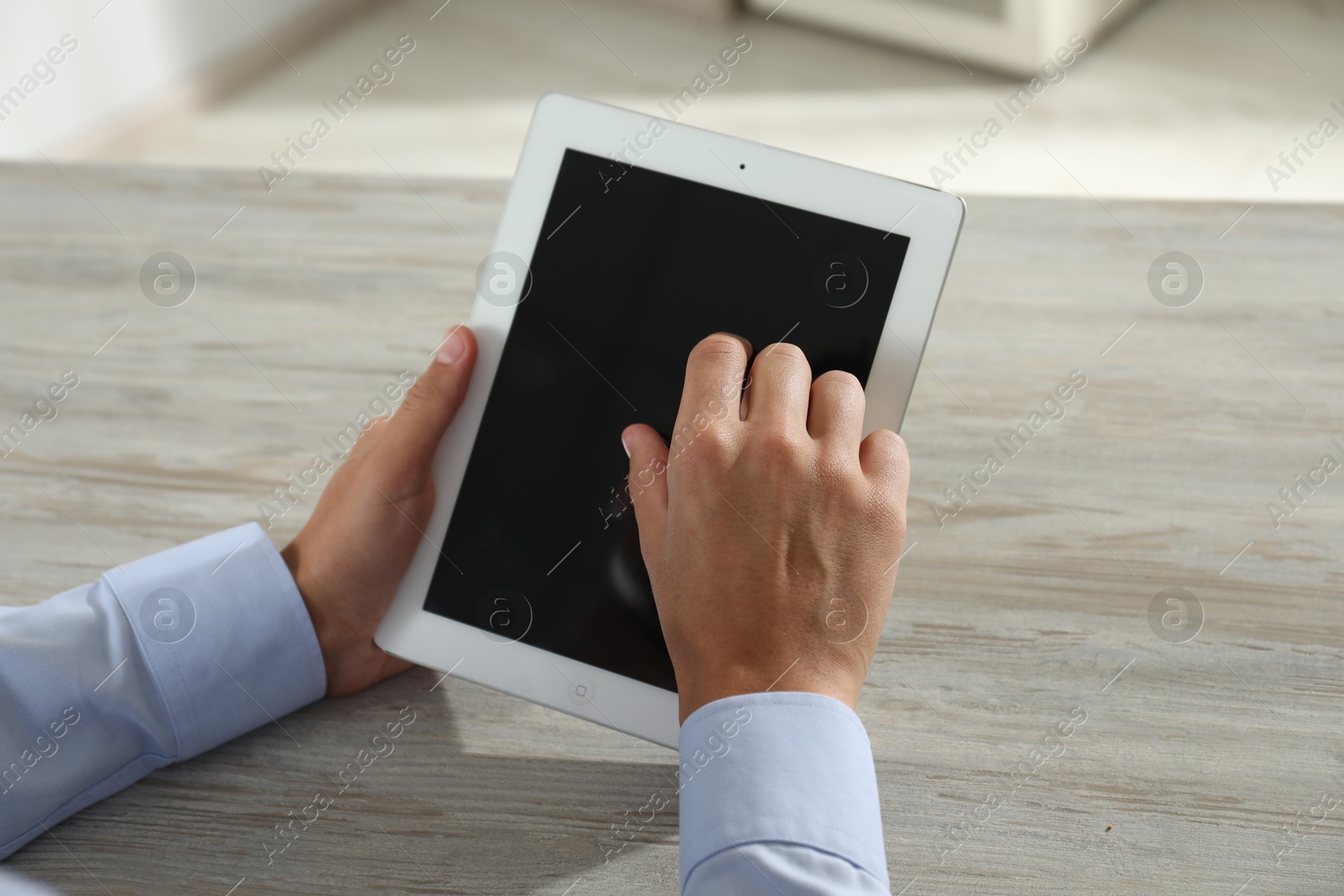 Photo of Businessman using tablet at wooden table, closeup. Modern technology