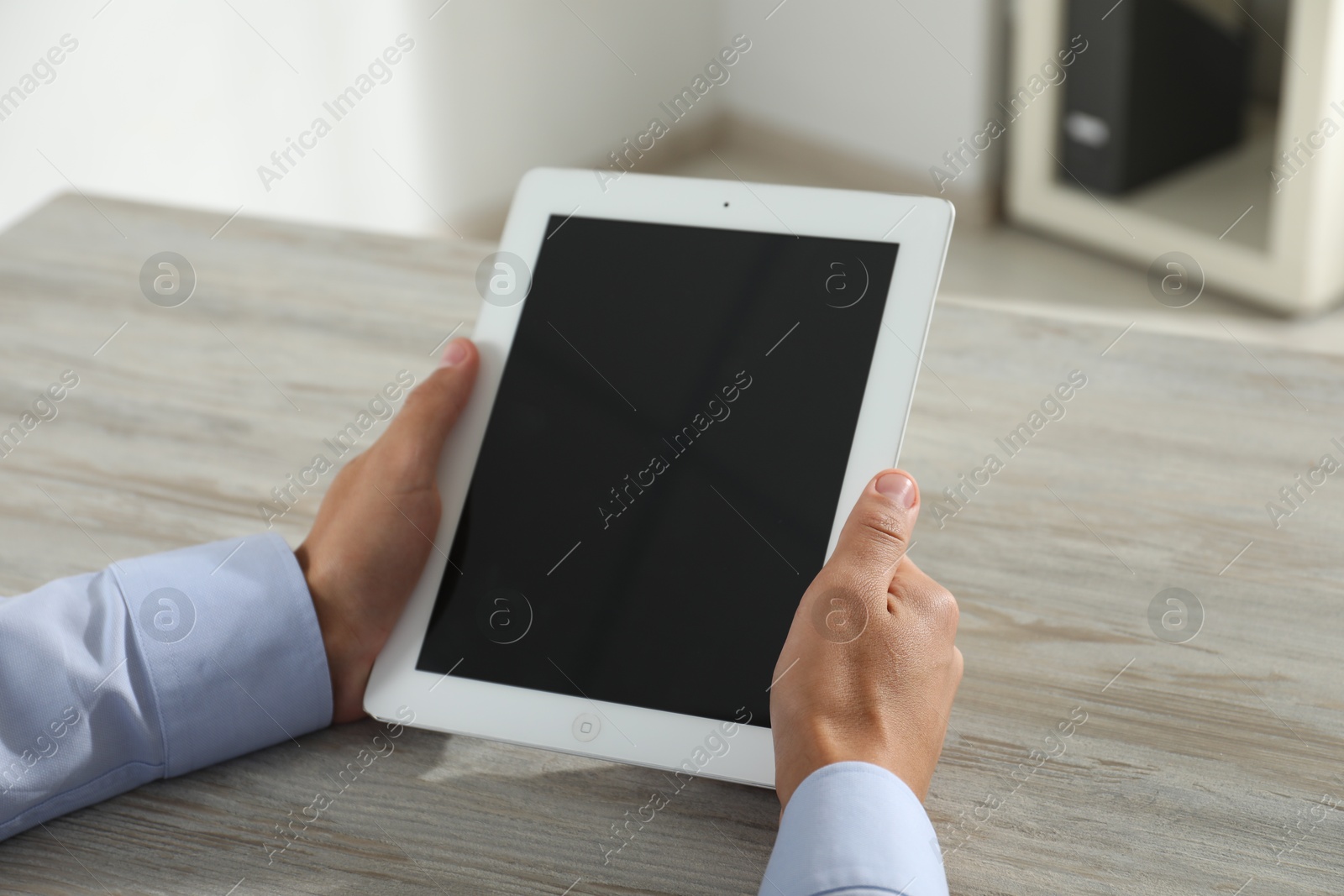 Photo of Businessman using tablet at wooden table, closeup. Modern technology