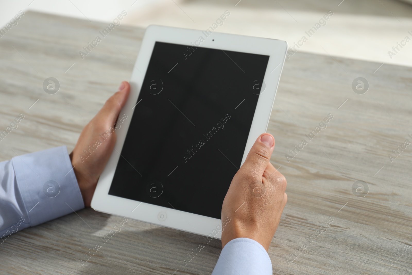 Photo of Businessman using tablet at wooden table, closeup. Modern technology