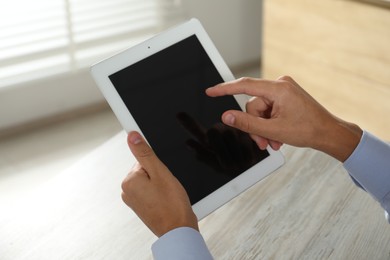 Photo of Businessman using tablet at wooden table, closeup. Modern technology