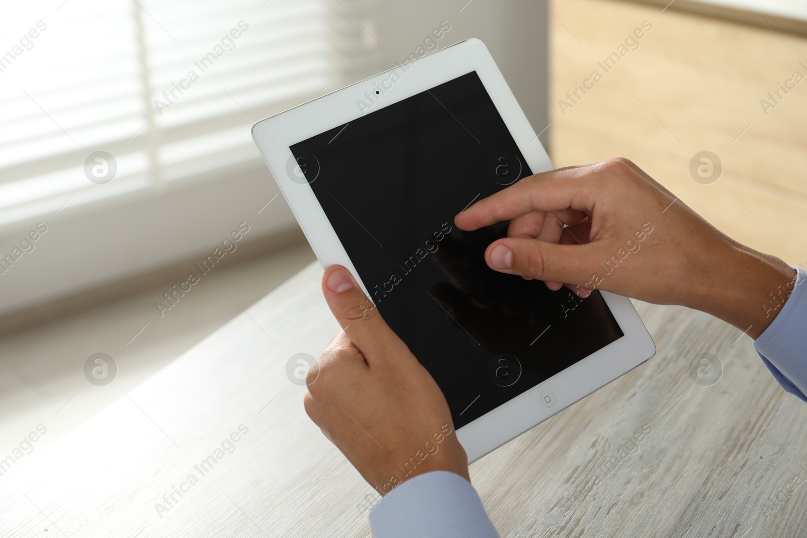 Photo of Businessman using tablet at wooden table, closeup. Modern technology