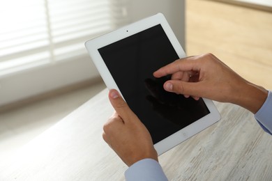 Photo of Businessman using tablet at wooden table, closeup. Modern technology