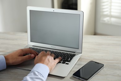 Photo of Businessman using laptop at wooden table, closeup. Modern technology