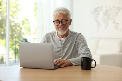 Senior man using laptop at table indoors