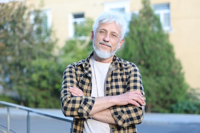 Photo of Portrait of senior man with crossed arms outdoors