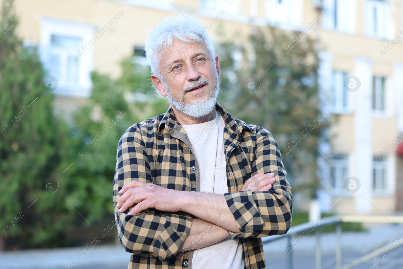 Photo of Portrait of senior man with crossed arms outdoors