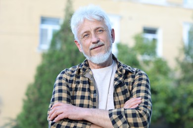 Photo of Portrait of senior man with crossed arms outdoors