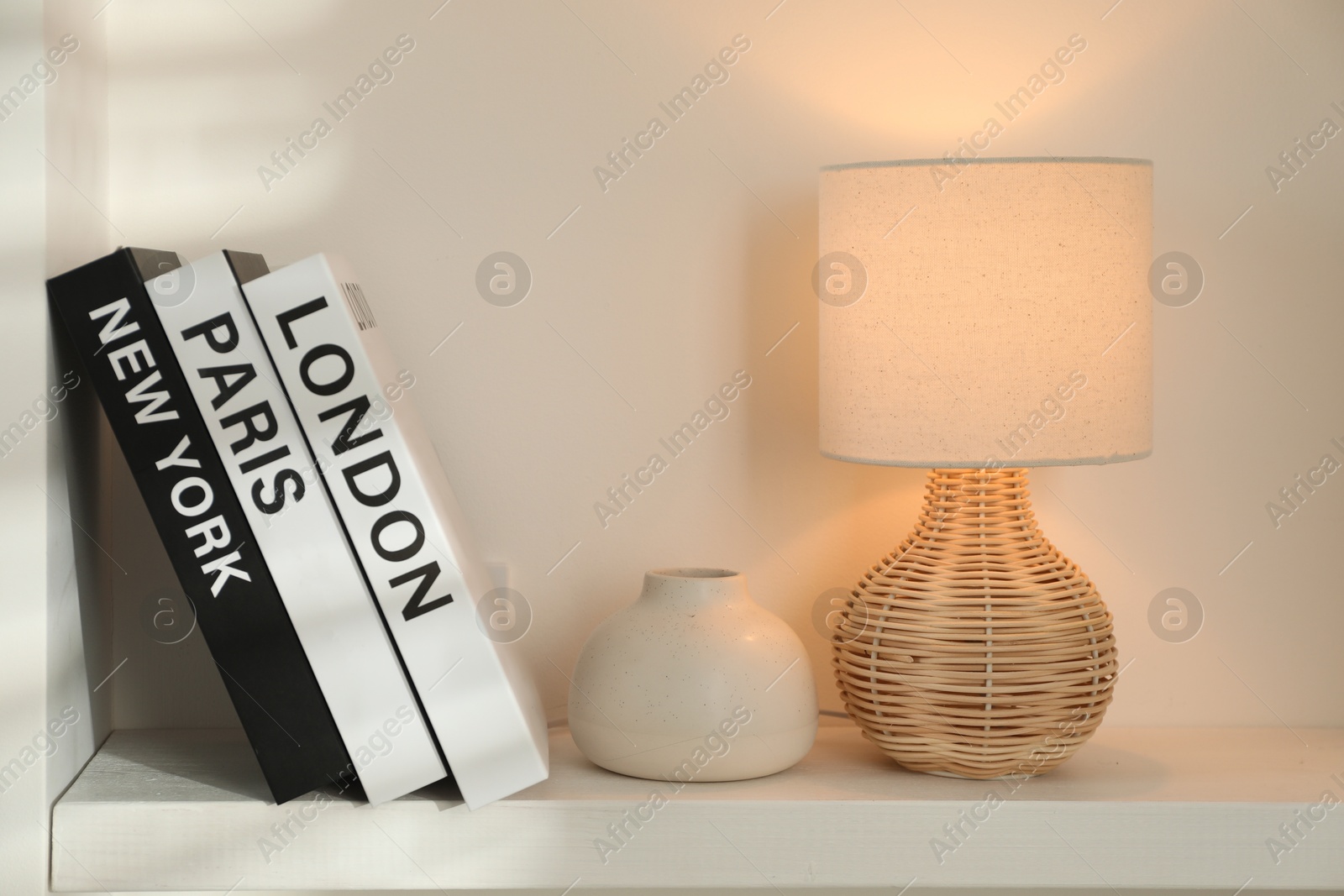 Photo of Lamp, ceramic vases and books on white shelf