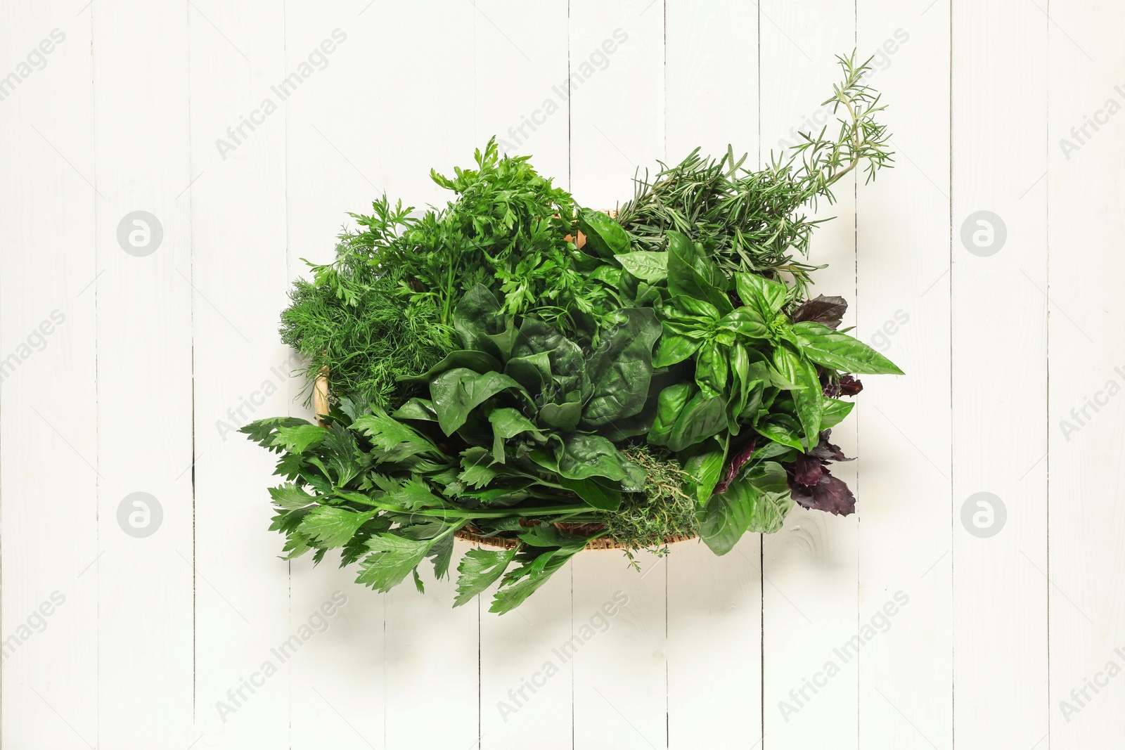 Photo of Different fresh herbs in basket on white wooden table, top view