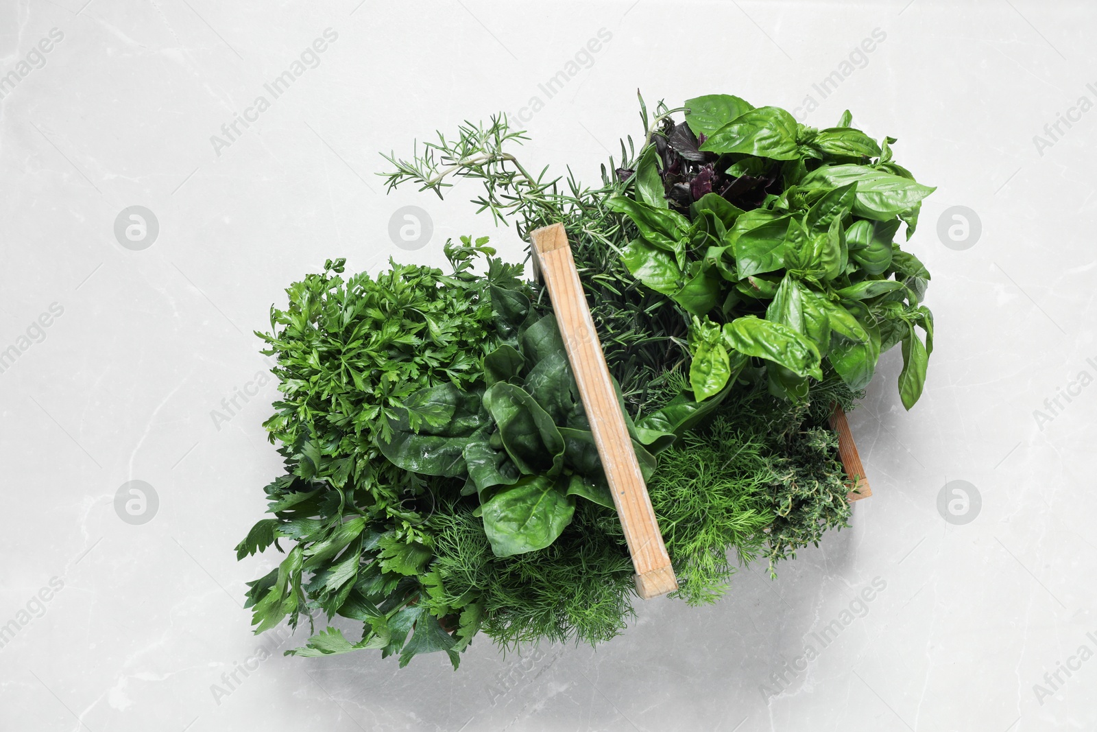 Photo of Different fresh herbs in wooden basket on light table, top view