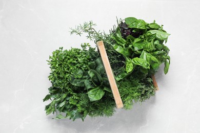 Photo of Different fresh herbs in wooden basket on light table, top view