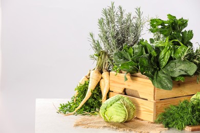 Different fresh herbs and cabbage on white table. Space for text