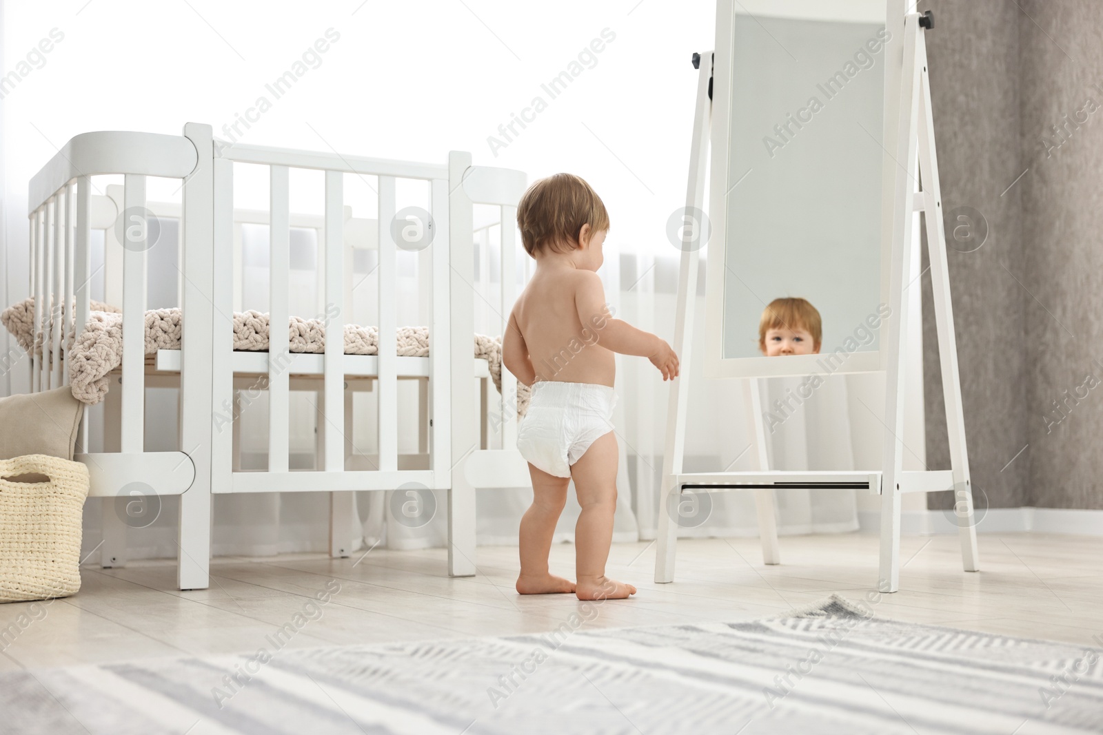 Photo of Little child in diaper near mirror at home