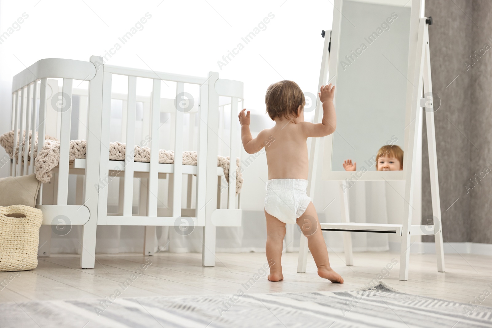 Photo of Little child in diaper near mirror at home